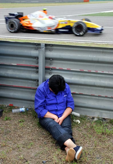 Eine Reinigungskraft macht neben der Formel 1 Rennstrecke in Shanghai ein Nickerchen. Eine Reinigungskraft macht neben der Formel 1 Rennstrecke in Shanghai ein Nickerchen.