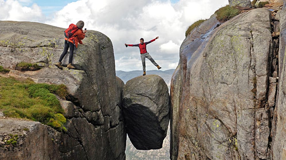 Ganz schön mutig: Eine Frau lässt sich auf einem fünf Kubikmeter großen Stein im Felsplateau Kjerag (Kiragg) in Norwegen fotografieren.
