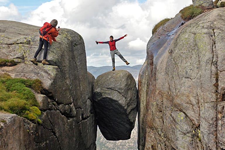Ganz schön mutig: Eine Frau lässt sich auf einem fünf Kubikmeter großen Stein im Felsplateau Kjerag (Kiragg) in Norwegen fotografieren.