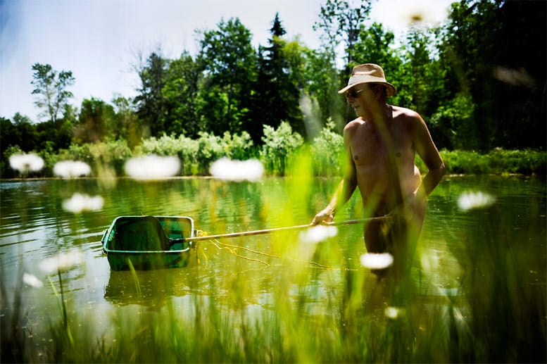 Beim Reinigen des Teiches genügt diesem Mann ein Strohhut als Sonnenschutz.