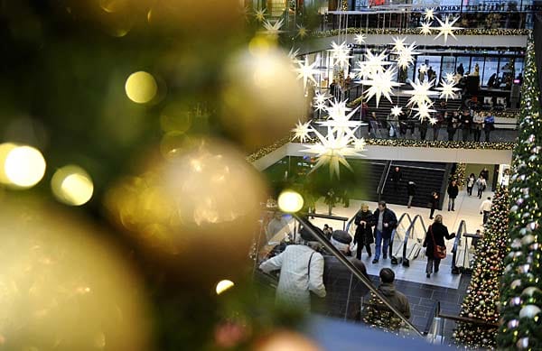 Passanten gehen in Dresden durch ein weihnachtlich geschmücktes Einkaufszentrum.
