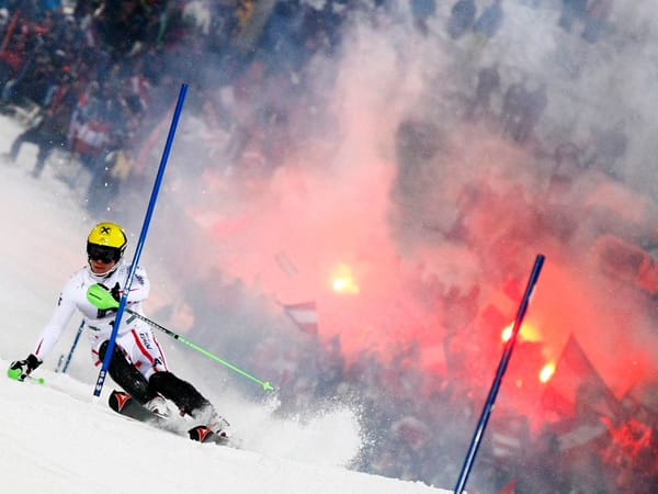 Österreichs Marcel Hirschner fährt beim Slalom-Weltcup in Schladming an einem Hindernis vorbei, seine Fans feiern derweil bereits den Gewinner.