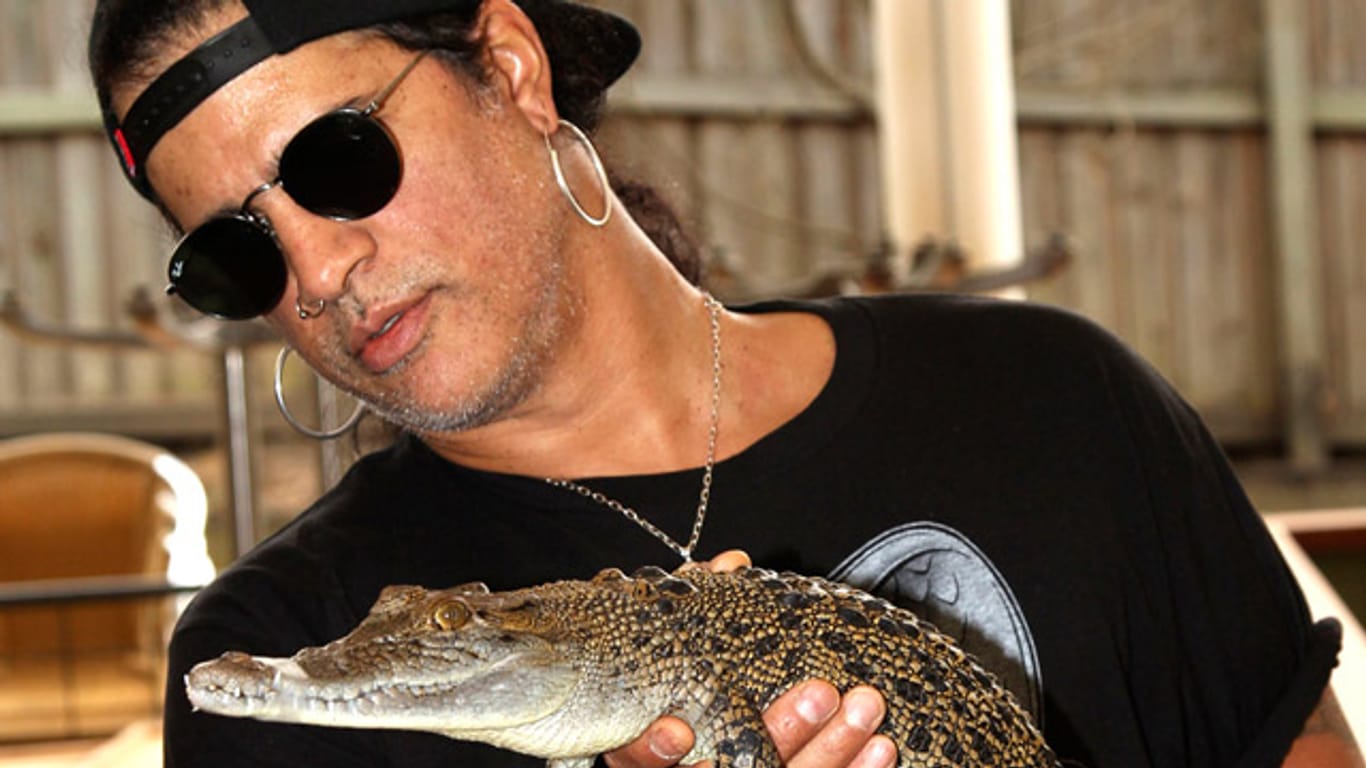 Wie seine Gitarre hat Slash auch das Baby-Krokodil fest im Griff.