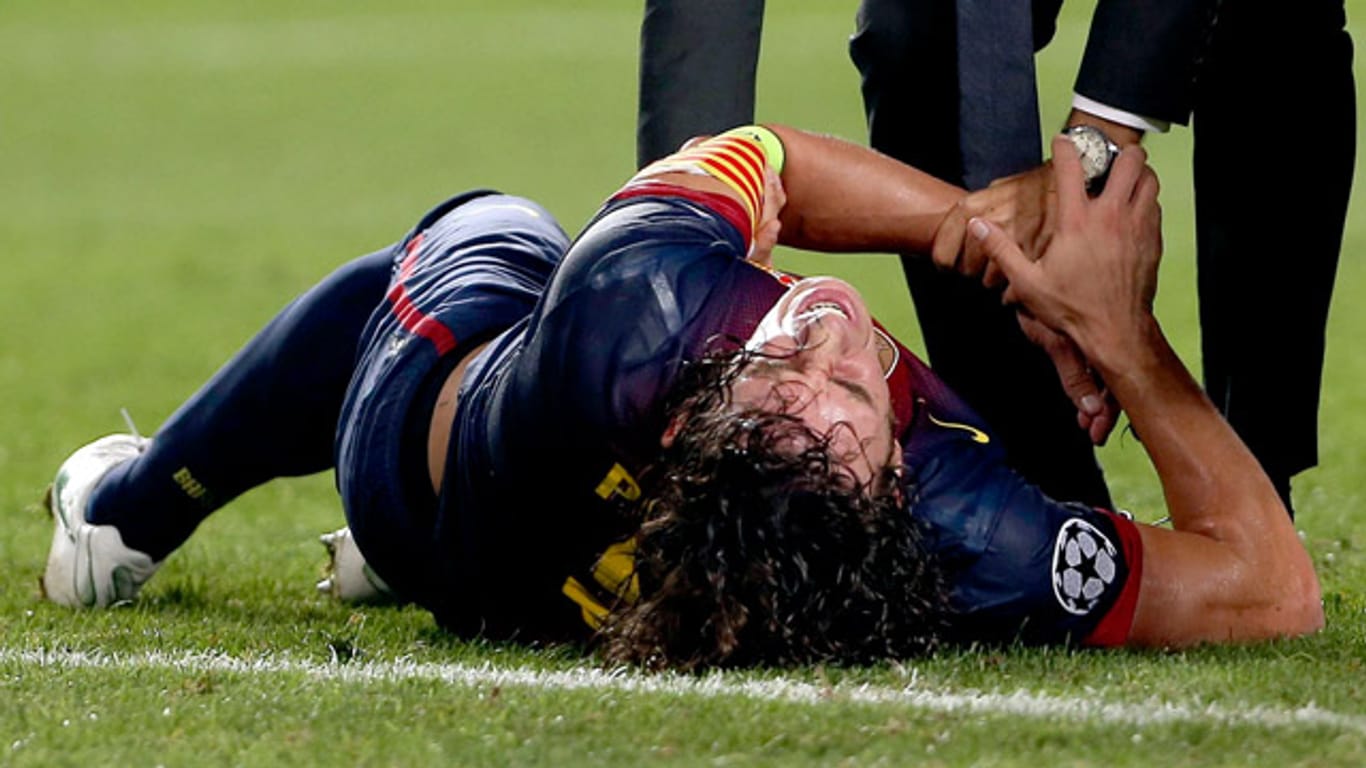 Carles Puyol vom FC Barcelona bleibt mit schmerzverzerrtem Gesicht auf dem Rasen liegen.
