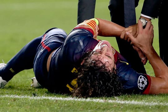 Carles Puyol vom FC Barcelona bleibt mit schmerzverzerrtem Gesicht auf dem Rasen liegen.