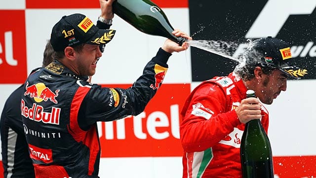 Sebastian Vettel (li.) lässt es auf dem Podium in Indien krachen.