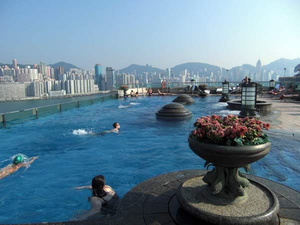 "Harbour Grand Kowloon", Hongkong: Der Pool ist rundum verglast und bietet den Gästen von der 21. Etage des Hotels aus einen fantastischen Blick auf die Bucht von Hongkong. Bequeme Liegestühle, Whirlpool und eine schicke Poolbar laden außerdem zum Relaxen ein.