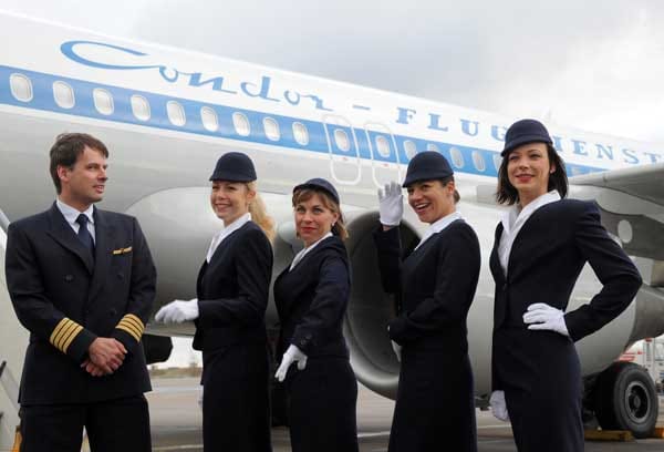 Condor: Dass die Airline eine Lufthansa-Tochter ist, spiegelt sich im Outfit wider. Neben den klassischen Farben Blau, Weiß und Gelb findet sich auch die traditionelle Pillbox, der runde Hut der Stewardessen, wieder.
