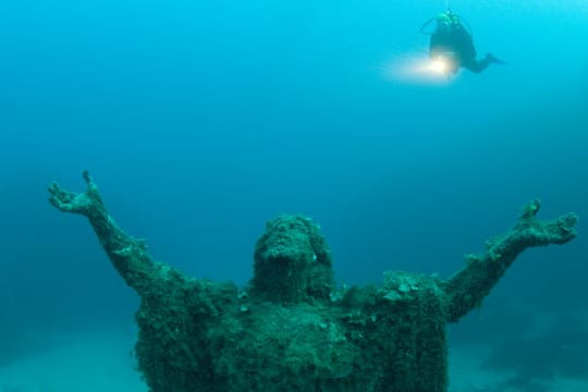 Mit offenen Armen empfängt die Christus-Statue Taucher.