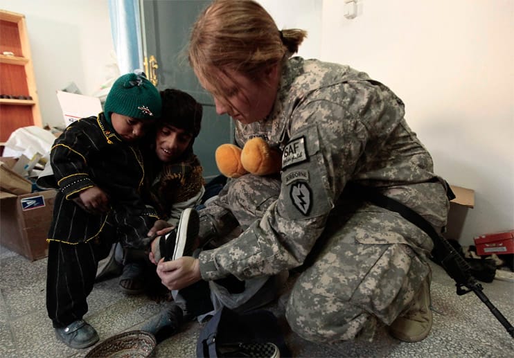 Eine US-Soldaten zieht einem kleinen afghanischen Jungen neue Schuhe an.