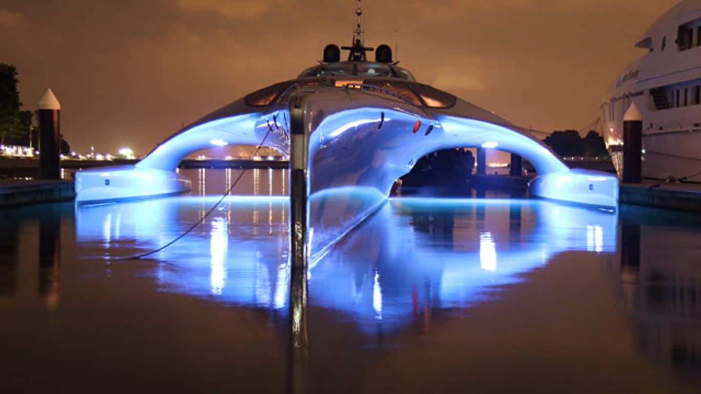 Die Superjacht Adastra liegt im Hafen von Hong Kong und erstrahlt bei Nacht ganz in blau.