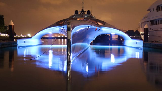 Die Superjacht Adastra liegt im Hafen von Hong Kong und erstrahlt bei Nacht ganz in blau.