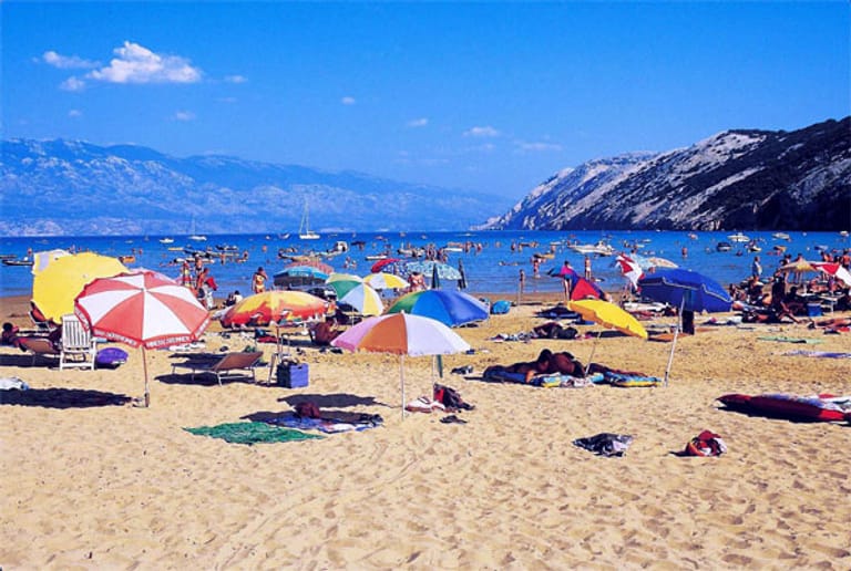 Bunte Schirme am Strand schützen vor der Sonne über Kroatien.