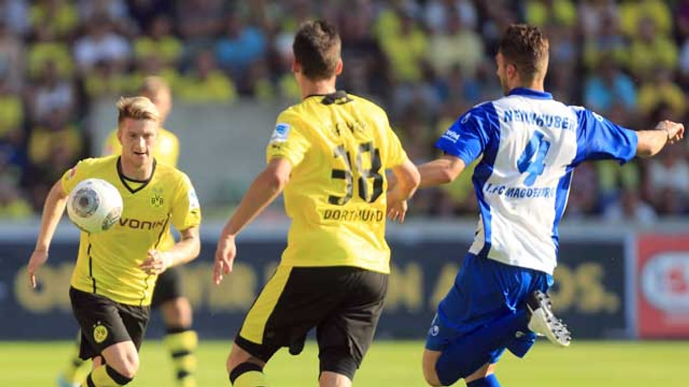 Dortmunds Marco Reus (li.) wird von einem Spieler des Regionalligisten 1. FC Magdeburg unter Druck gesetzt.