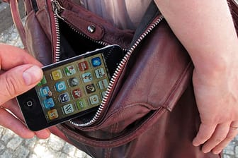Handy-Dieb zieht einer Frau das Smartphone aus der Tasche.