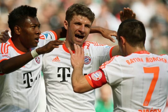 Die Bayern-Profis jubeln in den weißen Auswärts-Trikots mit orangen Akzenten.