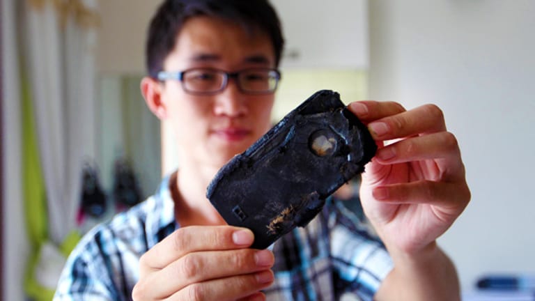 Der Chinese Wang Kai zeigt sein iPhone, das am Ladegerät hängend explodiert ist.