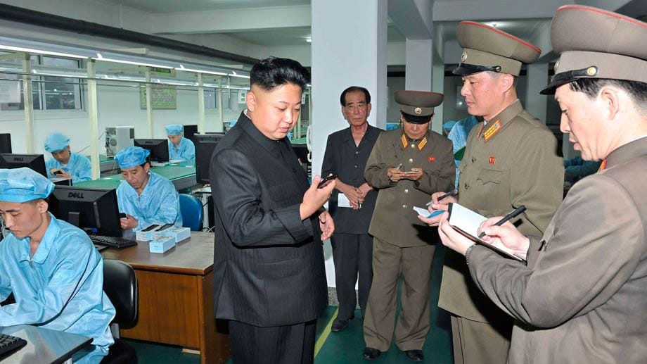 Der Diktator Kim Jong Un begutachtet in einer Firma das erste Smartphone aus heimischer Produktion.