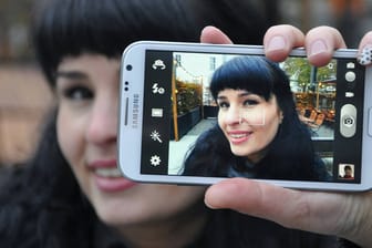 Frau zeigt Fotos auf ihrem Smartphone.