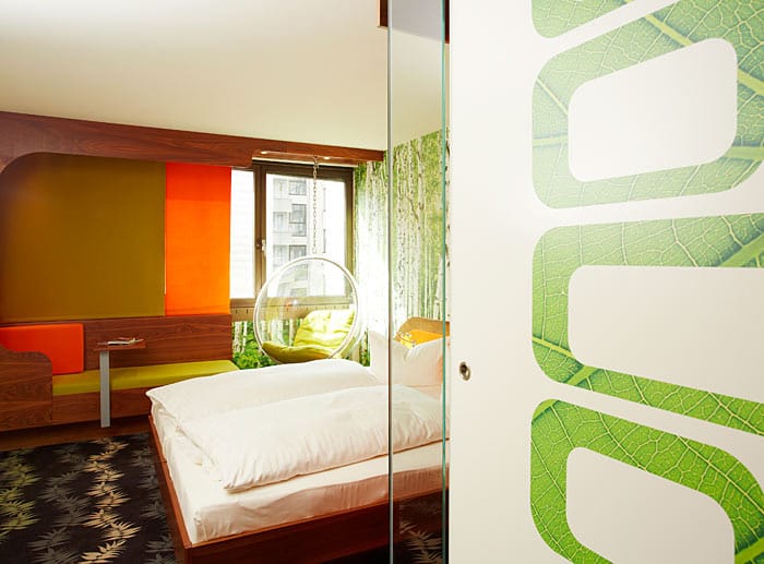 In den farbenfrohen Zimmern mit Retrolook finden sich Waldelemente in Form einer Waldfoto-Tapete wieder.