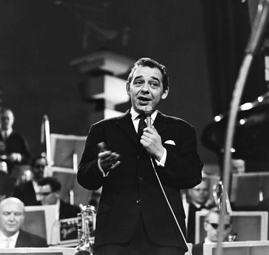 Paul Kuhn singend auf einer Bühne. Das Foto zeigt den Musiker ca. in den 60er Jahren.