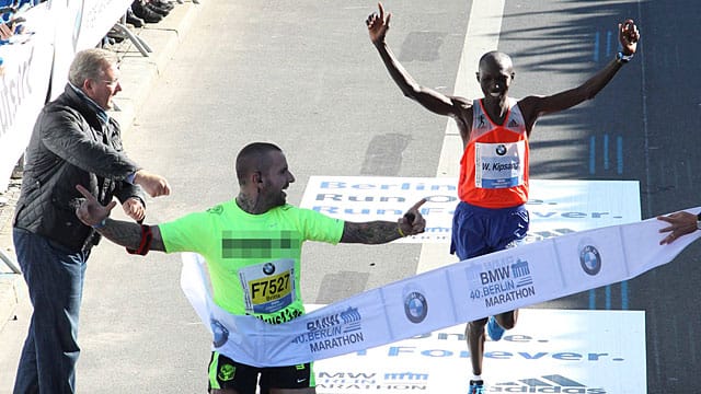 Ein Flitzer überquert beim Berlin-Marathon die Ziellinie vor dem Gewinner Wilson Kipsang.