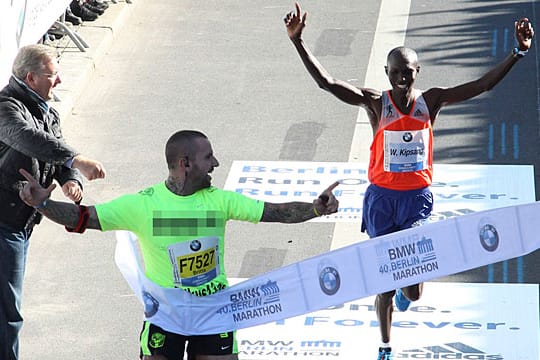 Ein Flitzer überquert beim Berlin-Marathon die Ziellinie vor dem Gewinner Wilson Kipsang.