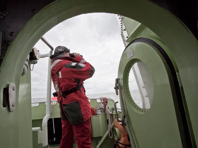 Ein Rettungsmann sucht das Meer während einer Suchaktion mit einem Fernglas ab.