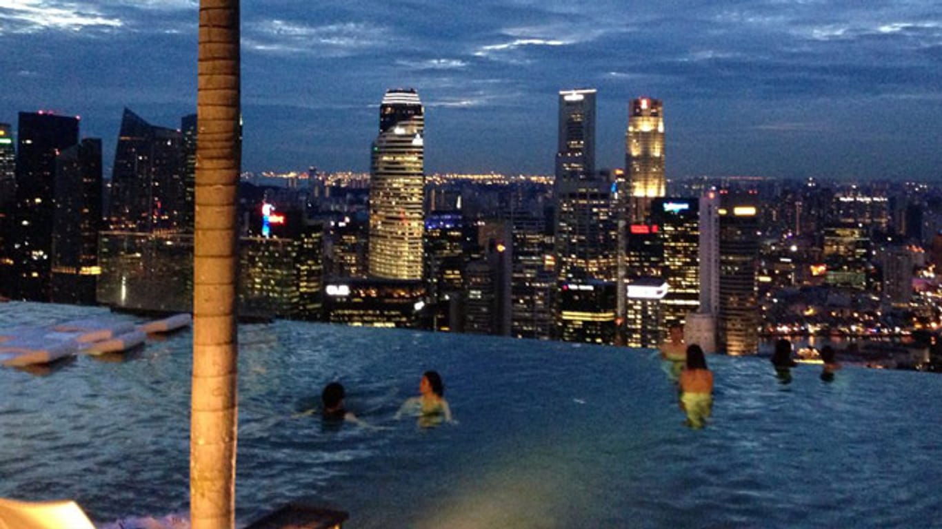 Im Infinity-Pool des "Marina Bay Sands“ in Singapur scheint die glänzende Silhouette der Stadt zum Greifen nah.