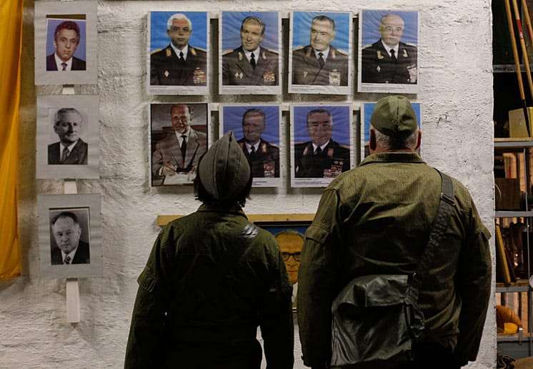 Zwei Teilnehmer des Erlebnisurlaubs im Stasi-Bunker betrachten sich Porträts von führenden Köpfen der ehemaligen Deutschen Demokratischen Republik.
