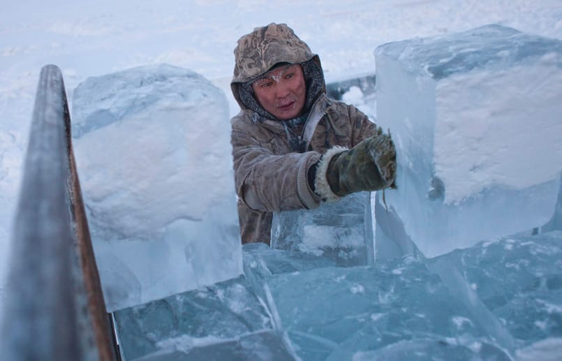Für Ruslan ist die Arbeit im Freien ganz normal. Mit dicken Handschuhen stapelt er Eisblöcke auf der Ladefläche eines LKW.