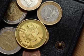 Eine Bitcoin-Münze zwischen Euro-Münzen.