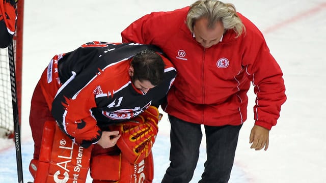 Torwart Robert "Bobby" Goepfert (li.) von der Düsseldorfer EG wird von einem Betreuer vom Platz geführt.