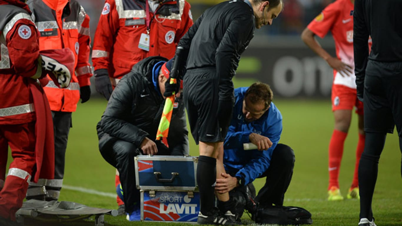 Minutenlang behandelt Freiburgs Physiotherapeut Uwe Vetter Schiedsrichter-Assistent Eric Dansault - vergeblich.