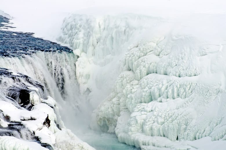 Der erstarrte Gullfoss-Wasserfall macht seinem Beinamen "Goldener Wasserfall" im schräg einfallenden Licht der Wintersonne alle Ehre. An anderen Tagen legen sich dichte Nebelschleier um den Wasserfall.
