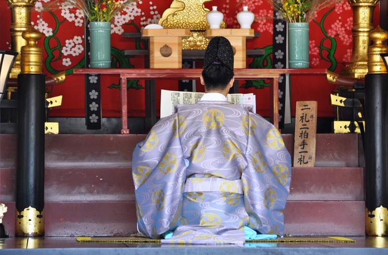 Ein Priester im Shinto-Schrein kniet andächtig nieder.