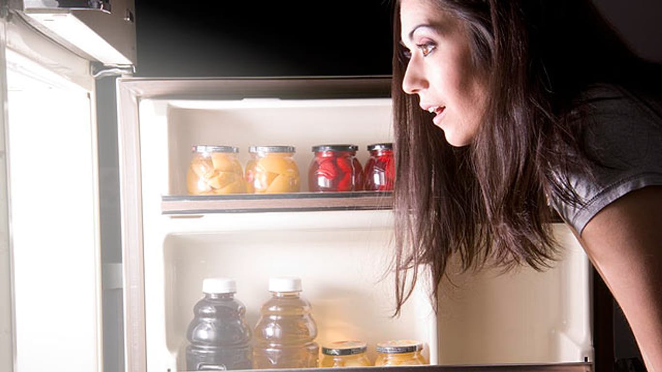 Frau blickt erstaunt in einen Kühlschrank