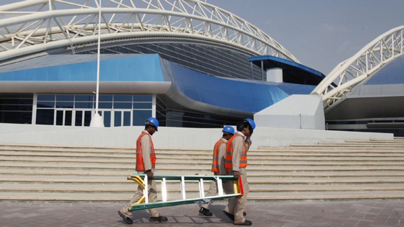 Erschöpfte Arbeiter laufen im Januar 2013 am Aspire Dome in Katar vorbei.