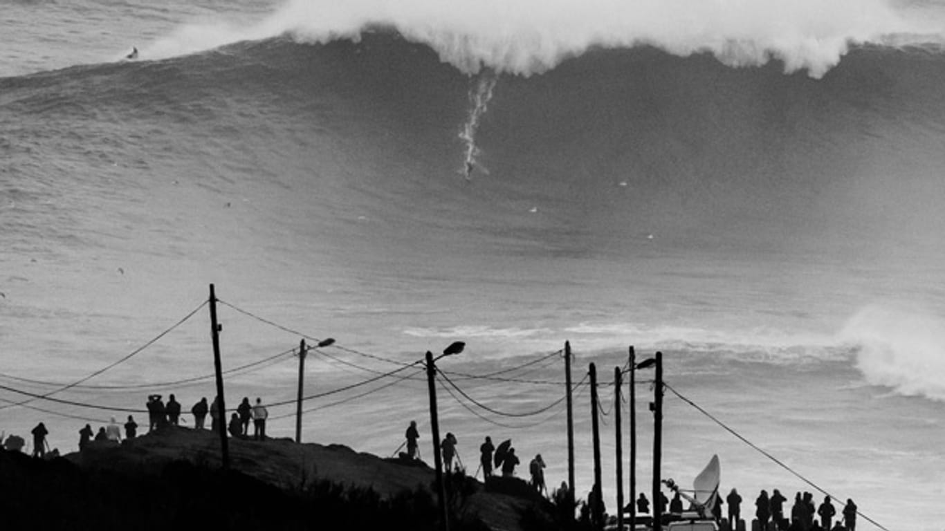 Schaulustige und Kamerateams beobachten Andrew Cotton beim Wellenreiten vor der portugiesischen Küstenstadt Nazaré.