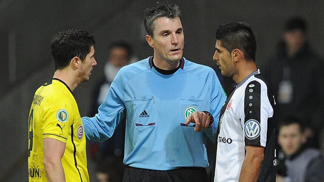 Referee Knut Kircher ermahnt Carlos Zambrano (re.) und Robert Lewandowski.