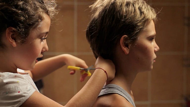 Szene aus dem Film Tomboy: Jeanne (Malonn Lévana) schneidet ihrer großen Schwester Laure (Zoé Héran) die Haare kurz.