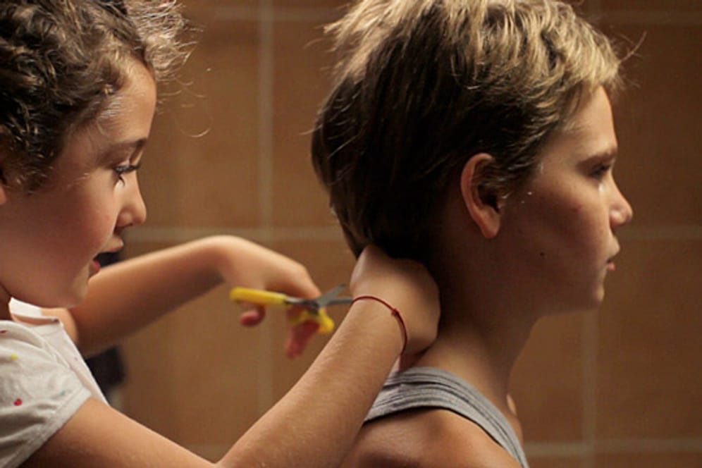 Szene aus dem Film Tomboy: Jeanne (Malonn Lévana) schneidet ihrer großen Schwester Laure (Zoé Héran) die Haare kurz.