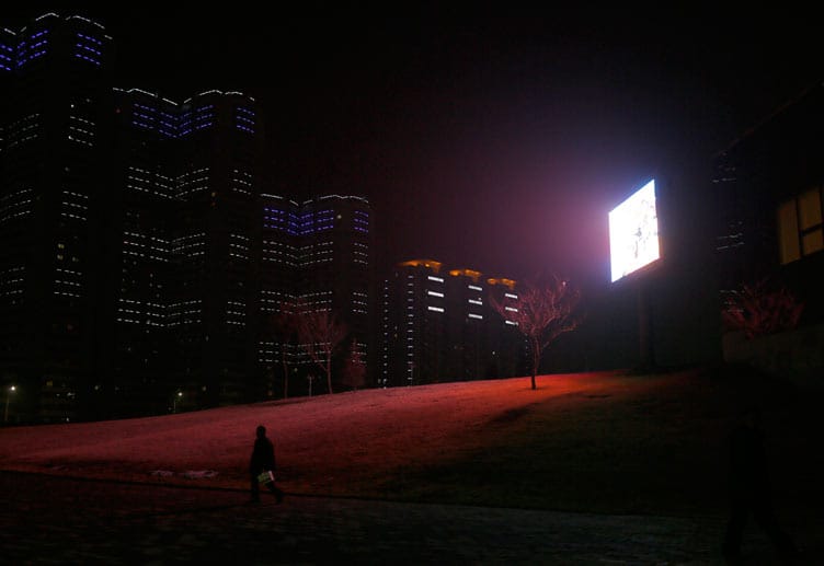 Ein Flatscreen mit Propaganda-Botschaften erhellt neben einem Wohnkomplex gespenstisch die Nacht.