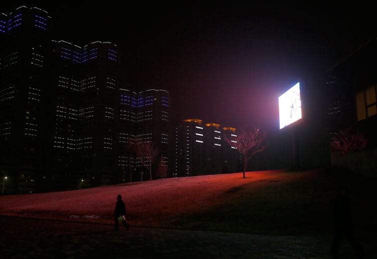 Ein Flatscreen mit Propaganda-Botschaften erhellt neben einem Wohnkomplex gespenstisch die Nacht. Ein Flatscreen mit Propaganda-Botschaften erhellt neben einem Wohnkomplex gespenstisch die Nacht.