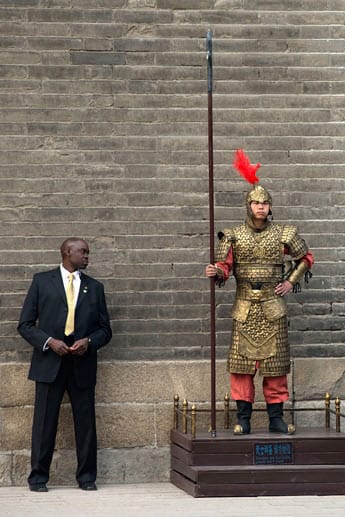 Wer hat die schönere Uniform? Ein US-Geheimdienst-Offizier begutachtet die alte Kriegeruniform eines Schaustellers, während Michelle eine Stadtmauer in Xi'an besichtigt.