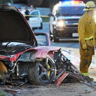 Feuerwehrmänner löschen den völlig zerstörten Sportwagen, in dem Paul Walker und Roger Rodas ums Leben kamen.