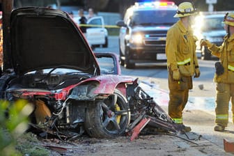 Feuerwehrmänner löschen den völlig zerstörten Sportwagen, in dem Paul Walker und Roger Rodas ums Leben kamen.