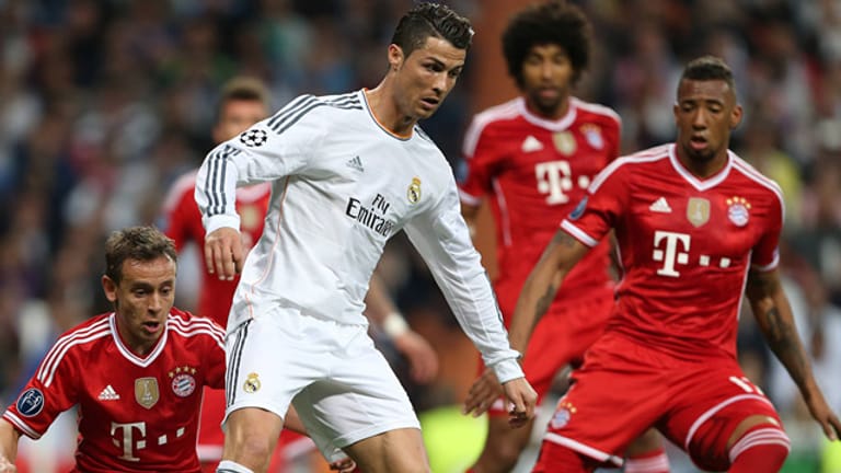 Real Madrids Superstar Cristiano Ronaldo behauptet den Ball gegen Bayern Münchens Rafinha (li.) und Jerome Boateng.