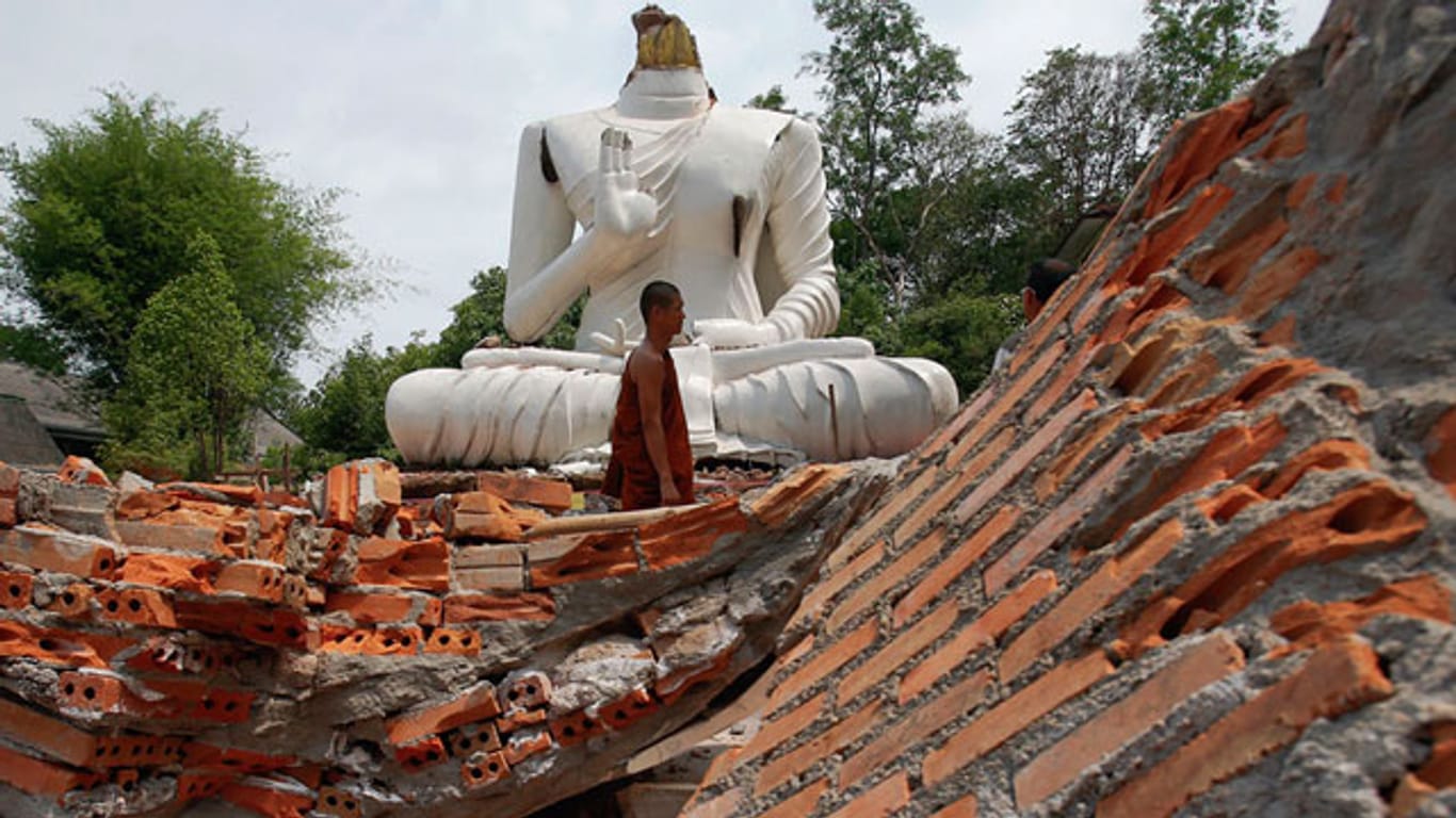 Ein buddhistischer Mönch vor einer durch das Beben zerstörten Buddha-Statue vor dem Udom Waree-Tempel in Chang Rai im Norden Thailands.