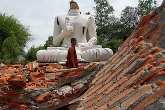 Ein buddhistischer Mönch vor einer durch das Beben zerstörten Buddha-Statue vor dem Udom Waree-Tempel in Chang Rai im Norden Thailands.